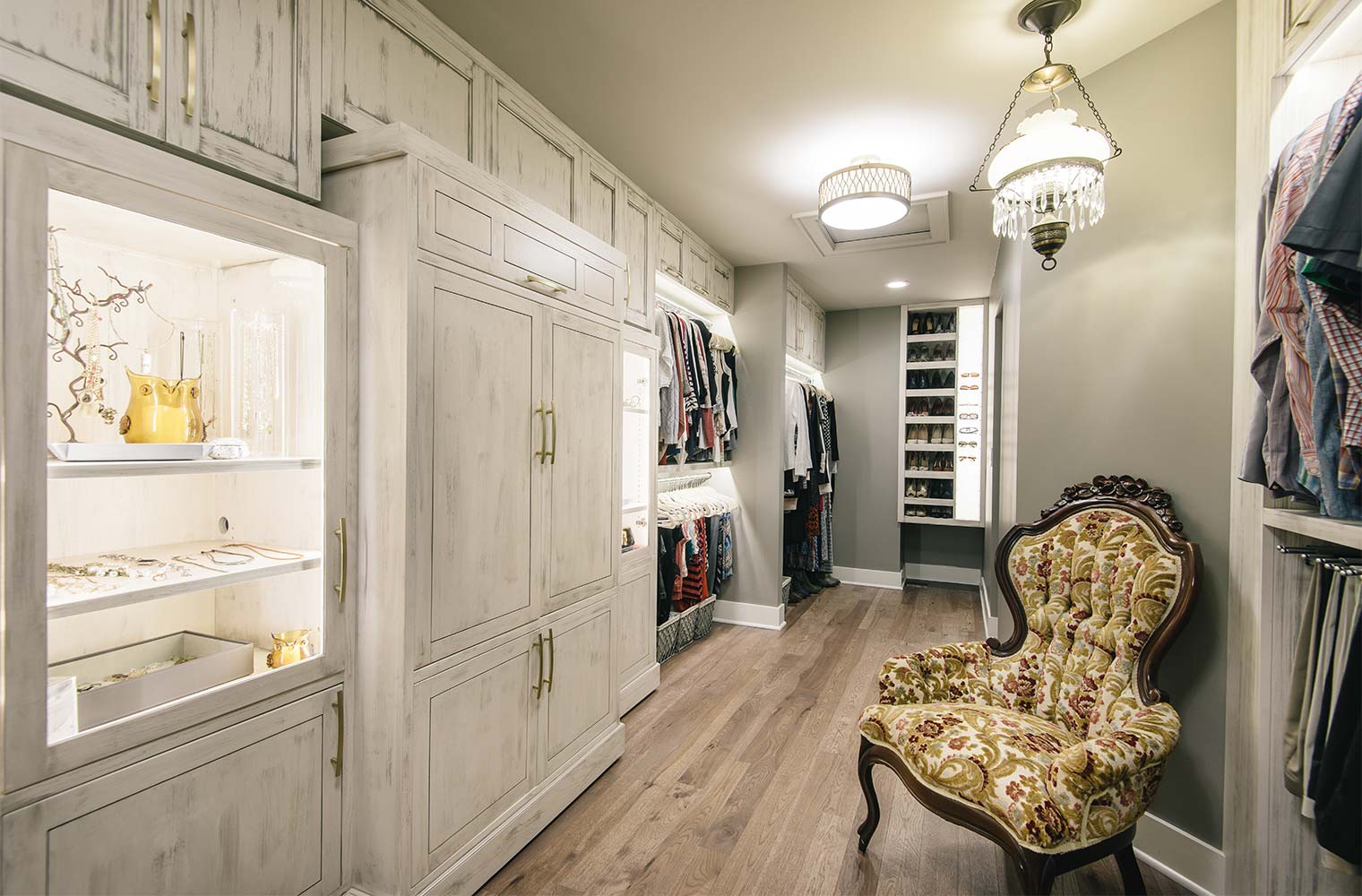 large walk-in closet with custom cabinets, lighted jewelry display cases, lighted sunglass display case, shoe cabinets and antique chandelier in master suite remodel by Silent Rivers of Des Moines