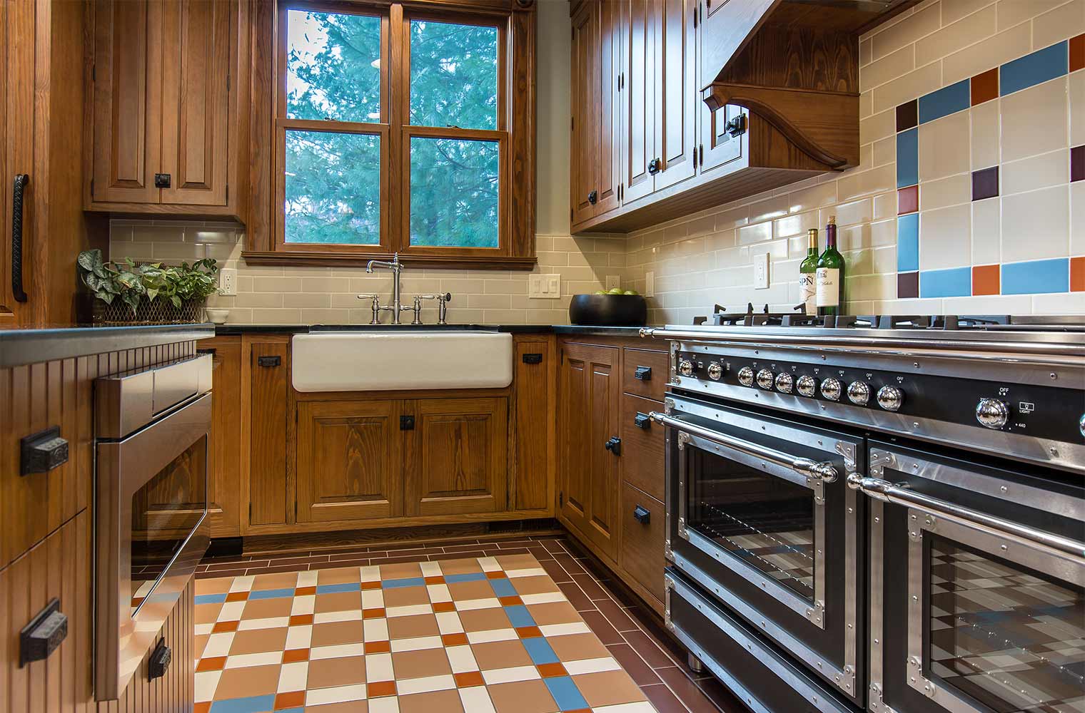 kitchen remodel in Des Moines Victorian home renovation by Silent Rivers includes commercial ovens, farmhouse sink, custom cabinets, floor tile and hardware that matches historic period