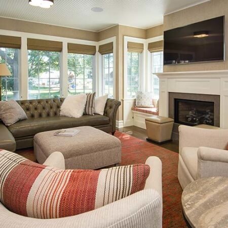 An addition Silent Rivers designed and built for a Colonial farmhouse in Des Moines creates a cozy sunroom with many windows, fireplace and headboard ceiling
