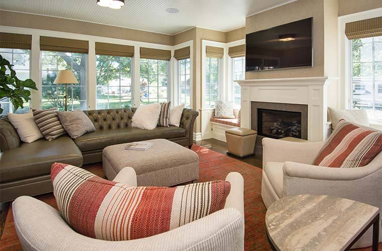 An addition Silent Rivers designed and built for a Colonial farmhouse in Des Moines creates a cozy sunroom with many windows, fireplace and headboard ceiling