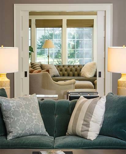 View from living room through pocket doors into a sunroom addition by Silent Rivers on a historic Des Moines colonial farmhouse.