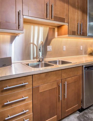 stainless steel countertop and backsplash with LED under cabinet lighting creates a striated effect in this downtown Des Moines loft remodel by Silent Rivers