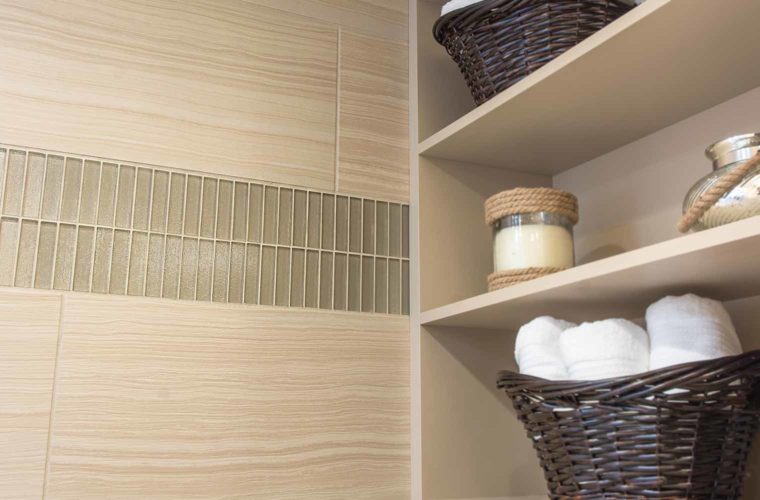 Vertical glass frieze tile runs from shower and out toward bathroom walls in this 1980s bathroom remodel by Silent Rivers, Des Moines