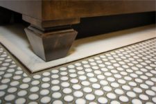 Penny round floor tile with metal accent strip around marble border tile and custom vanity with legs in bathroom remodel by Silent Rivers, Des Moines