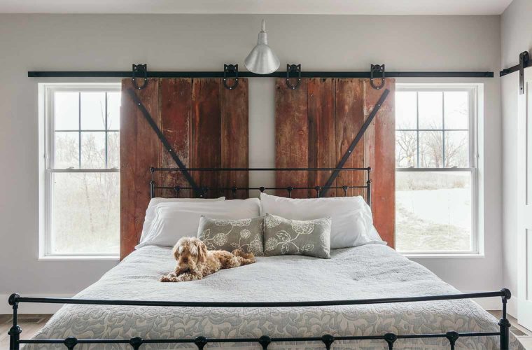 Sliding barn door window treatments in master bedroom of barn style custom new home designed and built by Silent Rivers of Des Moines, Iowa