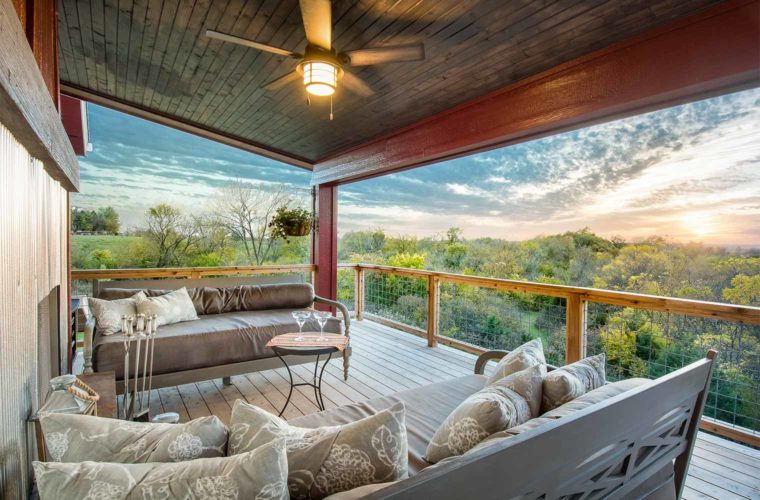 Barn style industrial farmhouse custom new home in St. Charles, Iowa designed and built by Silent Rivers features an upper deck with steel surround fireplace and stunning rural views