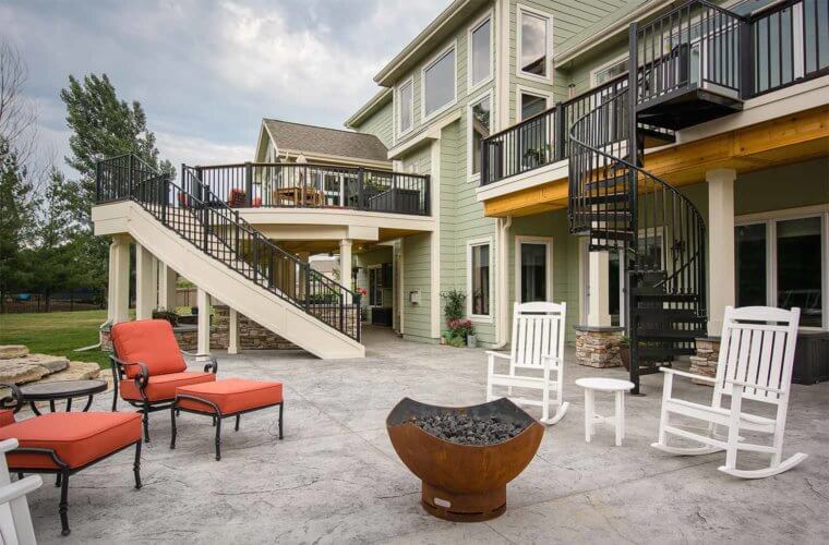 outdoor sitting area and fire bowl on curved patio and deck with curved staircases by builder Silent Rivers of Des Moines, Iowa