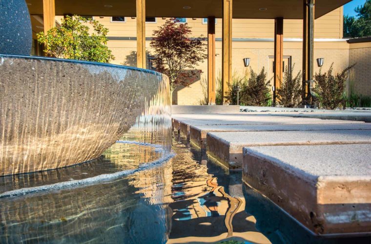 contemporary front entry courtyard with spherical water fountain with floating stepping stones in Johnston, Iowa by Silent Rivers