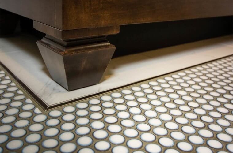 penny round tile flooring is bordered by white marble flooring under a custom bathroom vanity cabinets with legs in Des Moines bathroom by remodeler Silent Rivers