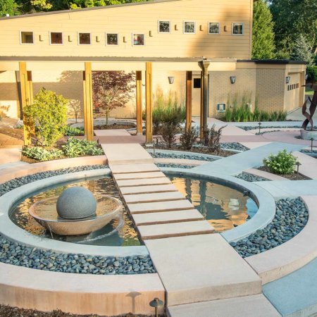 contemporary front entry courtyard with concentric circles, metal sculpture, spherical water fountain with floating stepping stones in Johnston, Iowa by Silent Rivers