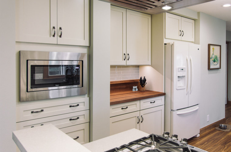 transition white and gray remodel of 1980s galley small kitchen in Des Moines by designer builder Silent Rivers features butcher block counter