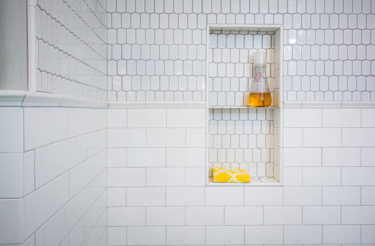 white elongated hexagonal tile above the white subway tile wainscot shower with inset shelf in Des Moines bathroom by remodeler Silent Rivers