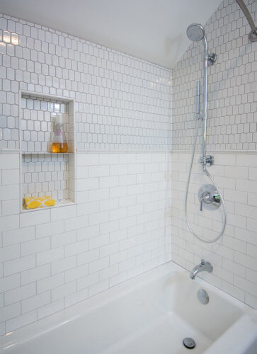 white elongated hexagonal tile above the white subway tile wainscot shower with inset shelf in Des Moines bathroom by remodeler Silent Rivers