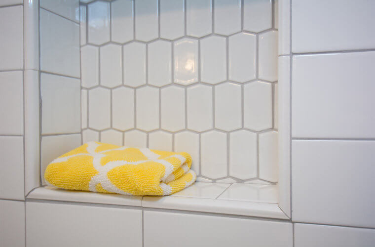white elongated hexagonal tile above the white subway tile wainscot shower with inset shelf in Des Moines bathroom by remodeler Silent Rivers